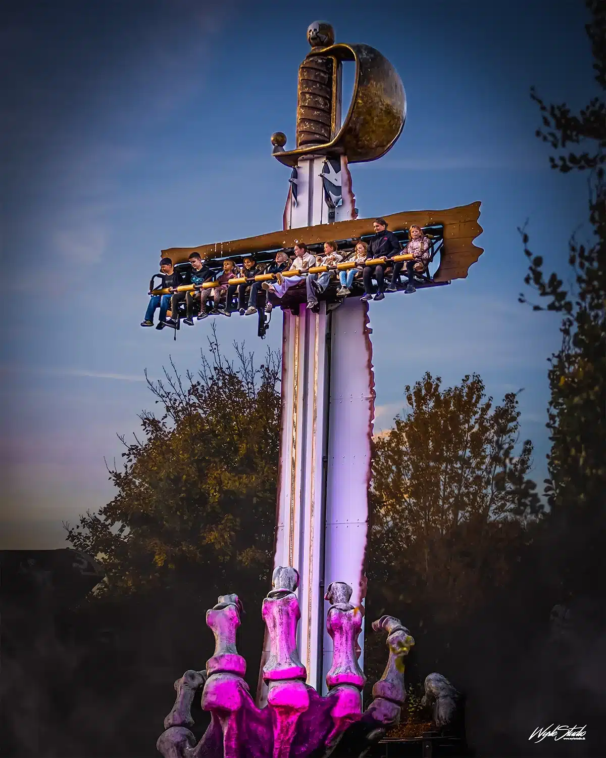 Forlystelse med sværd og børn i sæder under aftenhimlen i Djurs Sommerland Halloween After Dark