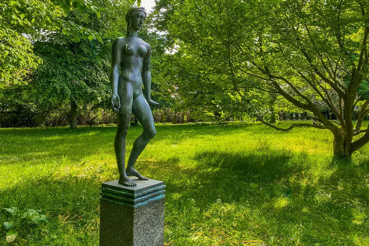 Skulpturen Den Svangre placeret midt i de frodige grønne omgivelser i Rådhusparken