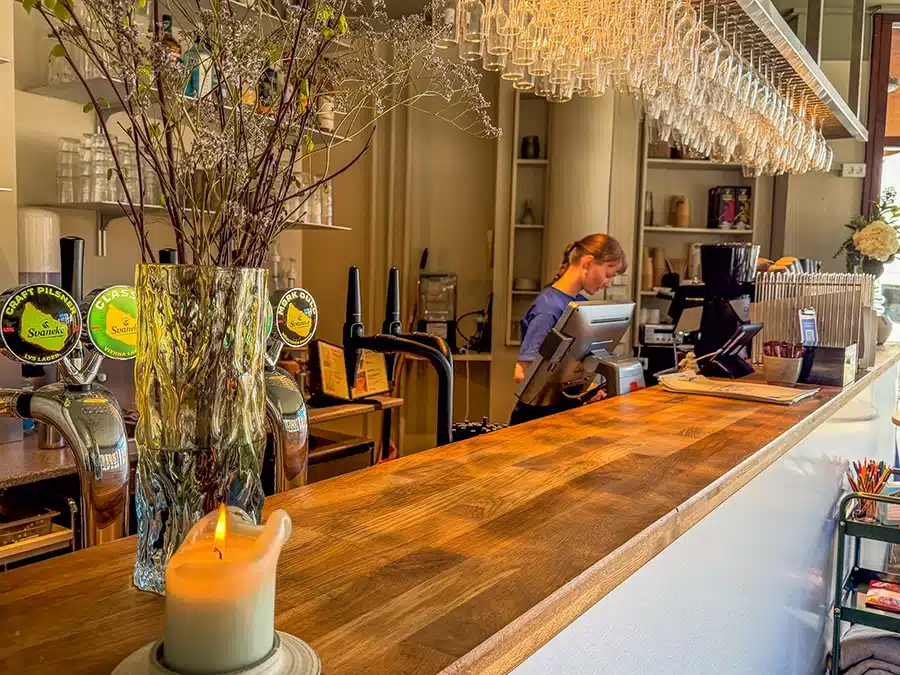 Hyggelig caféstemning hos Woodys i Aarhus med lang trædisk, levende lys, ølhaner fra Svaneke Bryghus