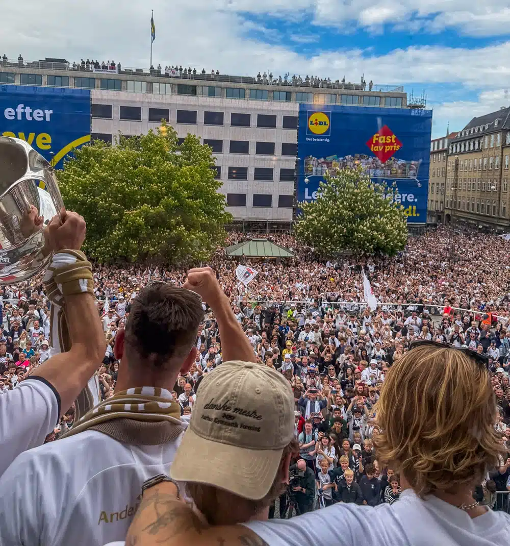 AGF-spillerne løfter pokalen og knytnæverne i vejret fra rådhusbalkonen ud over en fyldt Rådhusplads